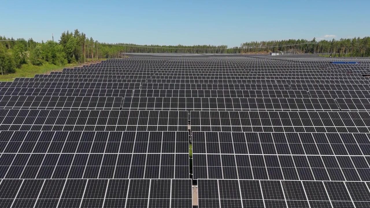 Un'ascesa aerea panoramica rivela un parco solare con pannelli e sistemi di alimentazione, un uso efficiente dell'energia rinnovabile in un'area boschiva aperta