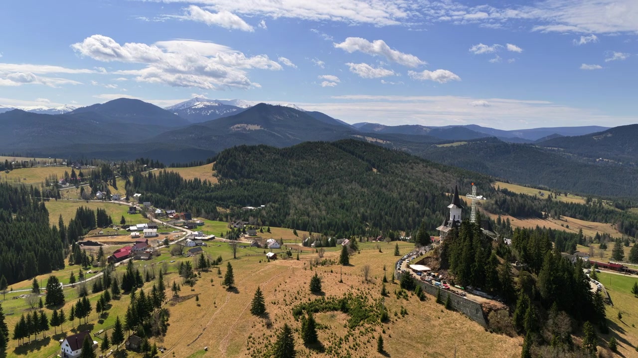 Vista aerea con drone dei Monti Carpazi vicino al Passo Mestecanis, con colline stratificate, foreste e cime innevate distanti.
