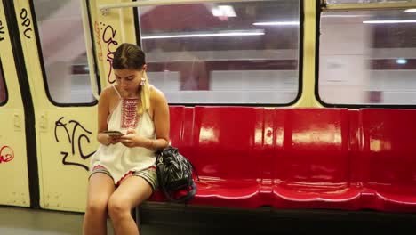 girl checking phone on old metro with graffiti