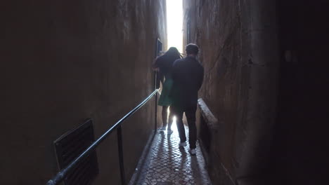 young couple running down narrow street in old city.