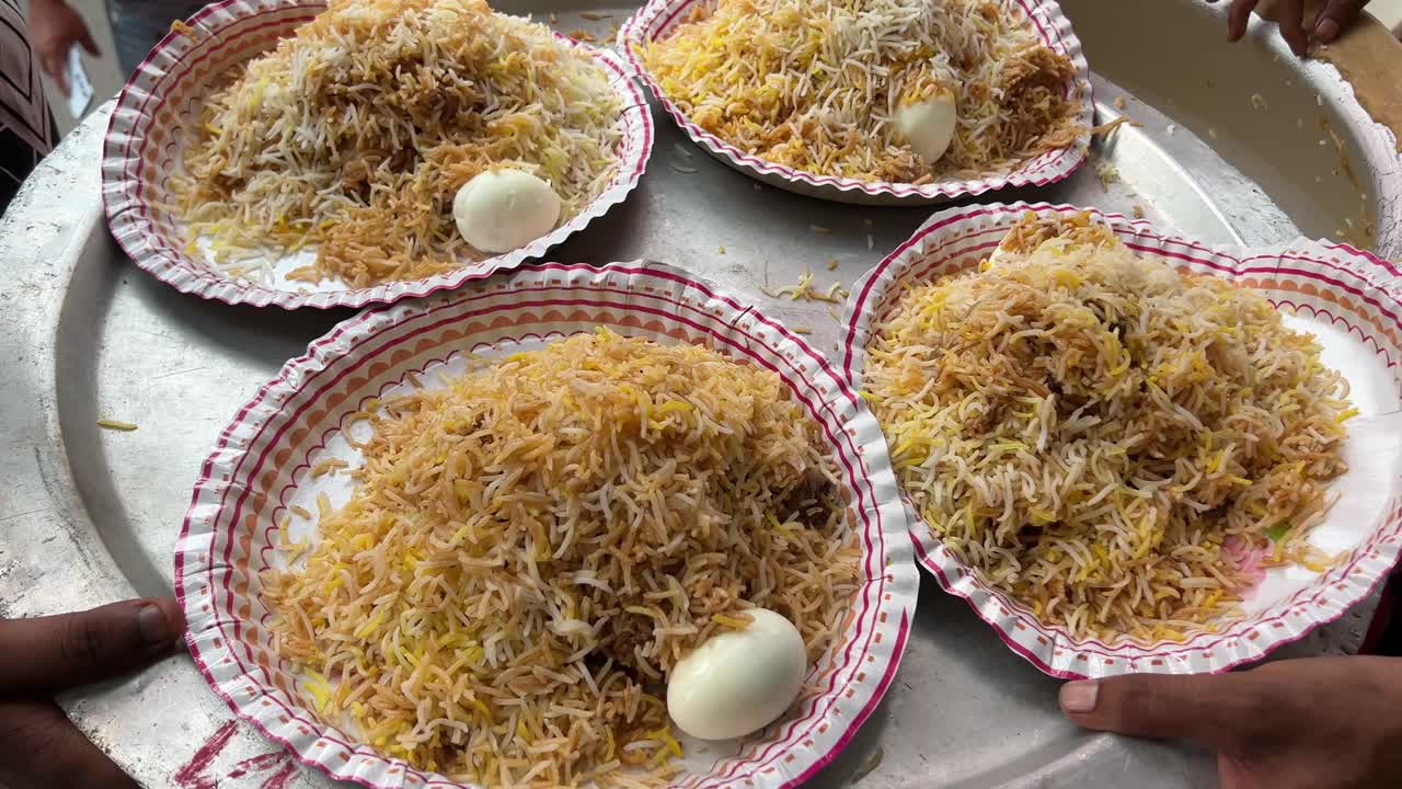 Four plates of Kolkata style mutton biryani served with potato and egg at a roadside stall in Kolkata.