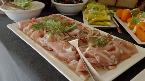 a table with snacks, on which there is a plate with cold cuts decorated with arugula