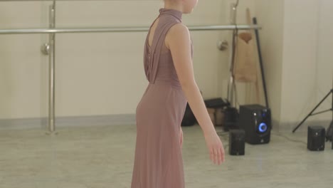 검은색 댄스웨어를 입은 젊은 발레 학생들이 나무 바닥과 벽에 장착된 바를 가진 넓은 발레 스튜디오에서 자세를 연습하는 그룹.