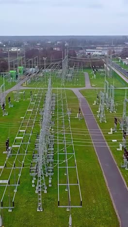 a cinematic parallax drone shot reveals the complex infrastructure of a large electrical substation in latvia, showing high-voltage power lines, transformers, and pylons that form the energy grid.