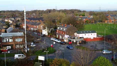 Small-village-traffic-junction-aerial-view-descending-to-vehicles-passing-community-neighbourhood-shops