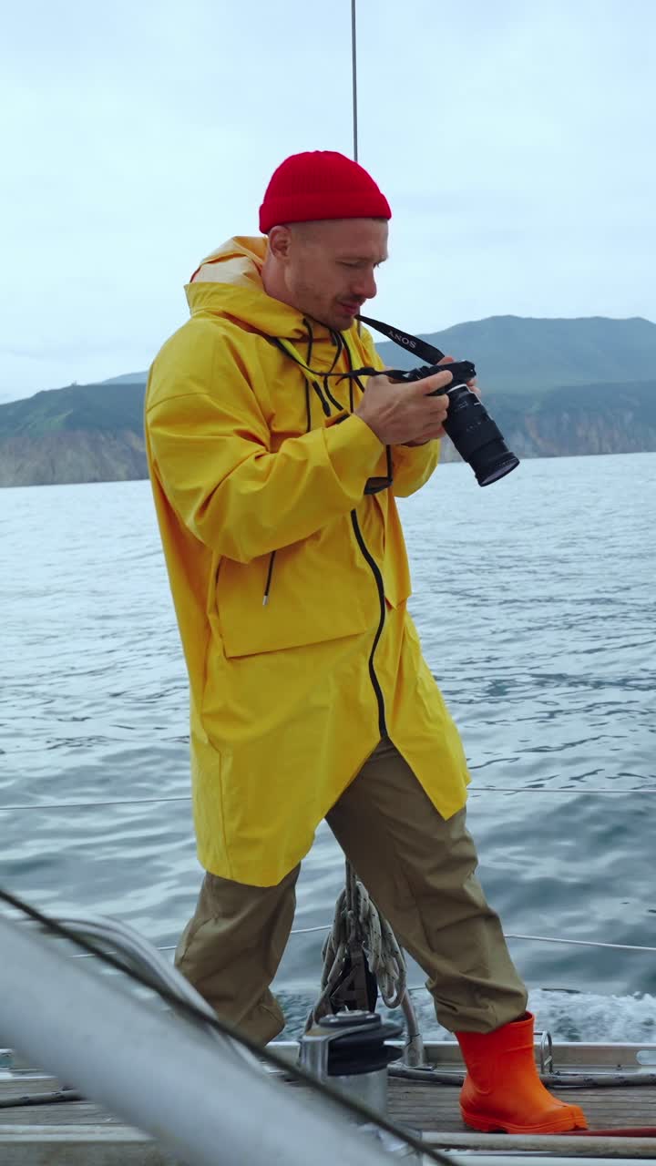 Man in Yellow Raincoat Taking Photos from a Boat