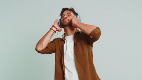 Happy-funny-Indian-man-in-headphones-listening-music-dancing-disco-having-fun-relaxing-on-party