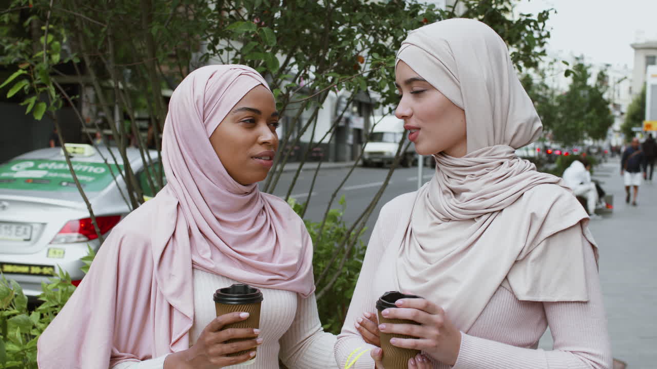 Two Women in Hijabs Enjoying Coffee Outdoors