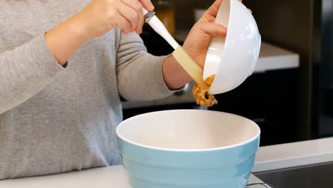 Woman-adding-ingredients-to-bowl-for-baking