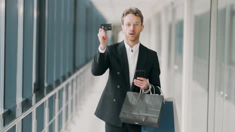 stylish business man with paper bags shows a credit card