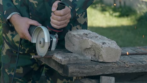 craftsman cuts metal rod with modern instrument in yard