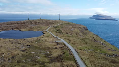 White-campervan-driving-at-an-scenic-road-between-wind-turbines-at-Feroe-Islands
