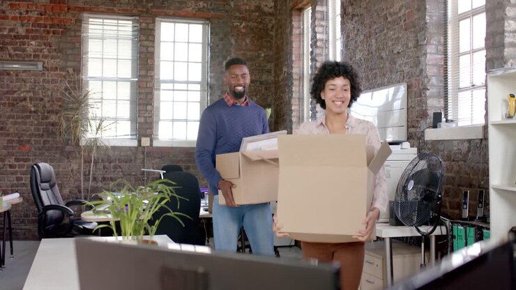 Happy diverse colleagues holding boxes with documents and office items in slow motion