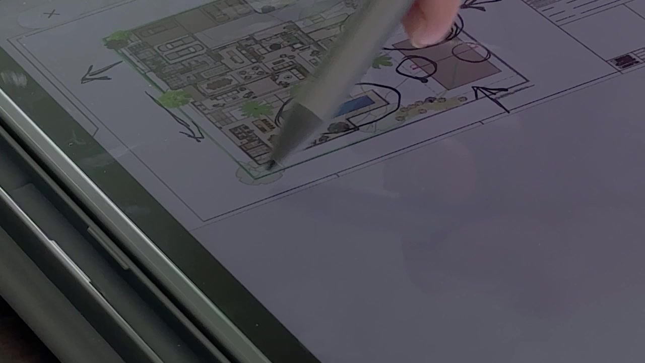 Using digital stylus on a tablet device to review and edit an architectural floor plan, illustrating modern design, planning and creative technology, close-up view