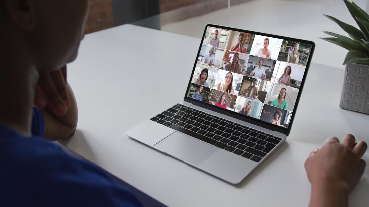 Donna afroamericana ripresa a mezzo busto in videoconferenza sul laptop con colleghi in ufficio