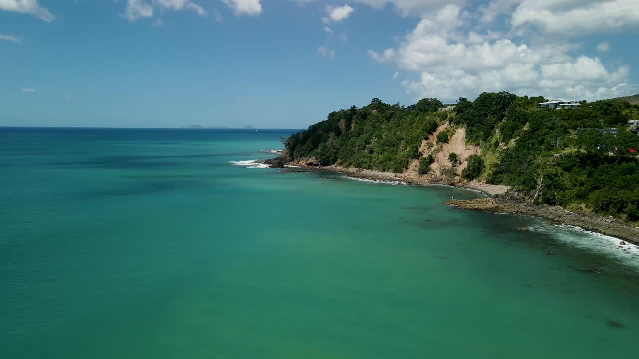 Cime di scogliere montuose dominano il famoso spot per il surf della Nuova Zelanda a Hot Water Beach