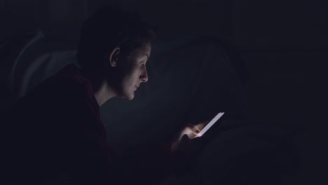 person using smartphone in bed at night