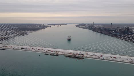 cargo ship on detroit river with gordie howe bridge in aerial view