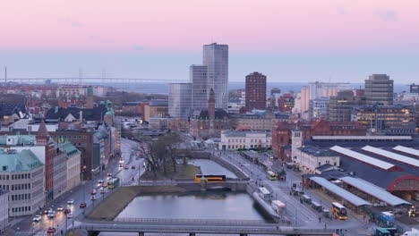 Drone-Crepuscular-Sobre-Canales-Cerca-De-La-Estación-Central-De-Malmo,-Puente-De-Oresund-En-El-Horizonte