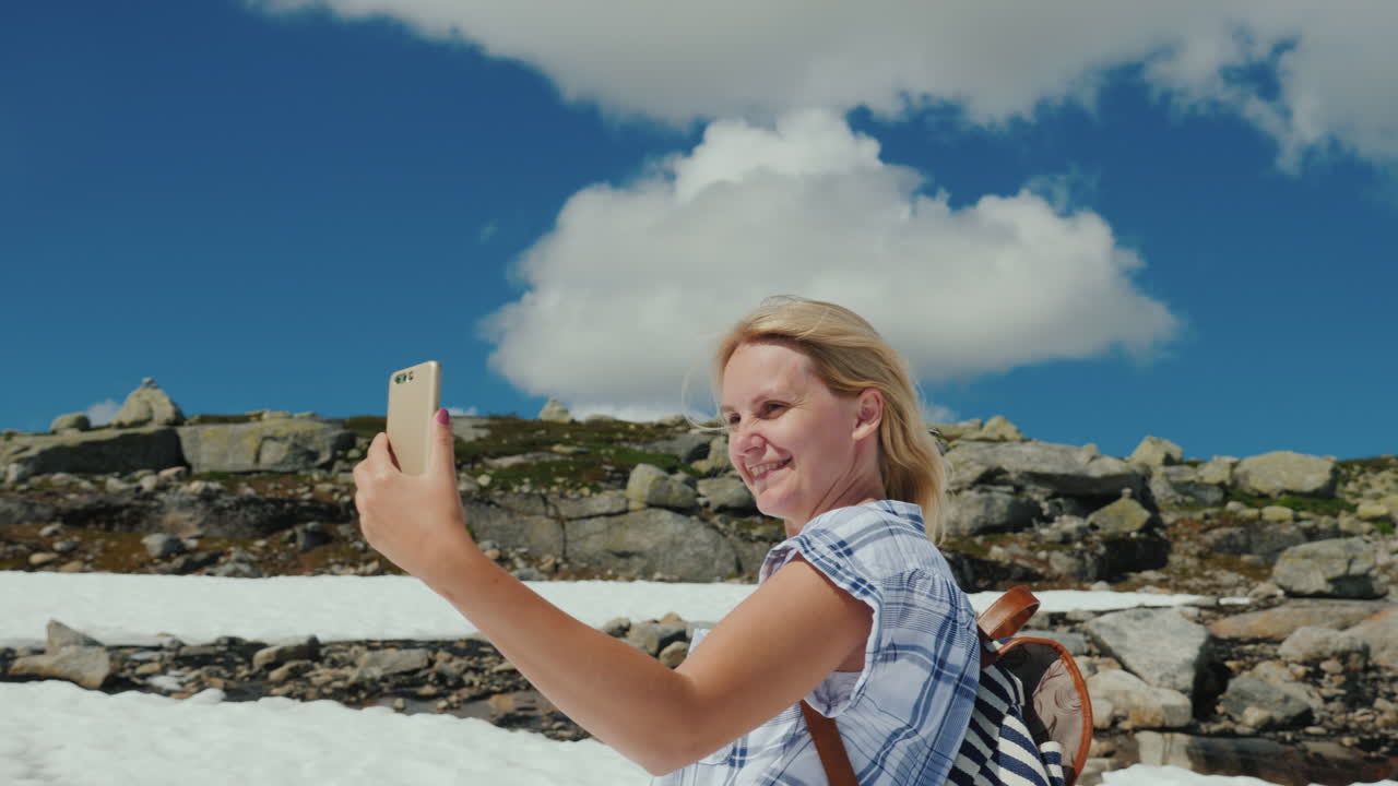 una mujer feliz haciendo selfie en un glaciar en noruega hace calor pero la nieve aún no se ha derretido la mañana