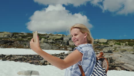 una mujer feliz haciendo selfie en un glaciar en noruega hace calor pero la nieve aún no se ha derretido la mañana