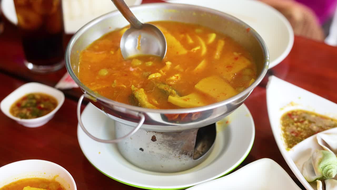 una secuencia que muestra una olla humeante de sopa tailandesa que se sirve en un restaurante en krabi, tailandia, con colores vibrantes y especias