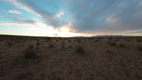 flight through expansive desert landscape at sunset with dynamic sky and distant mountains