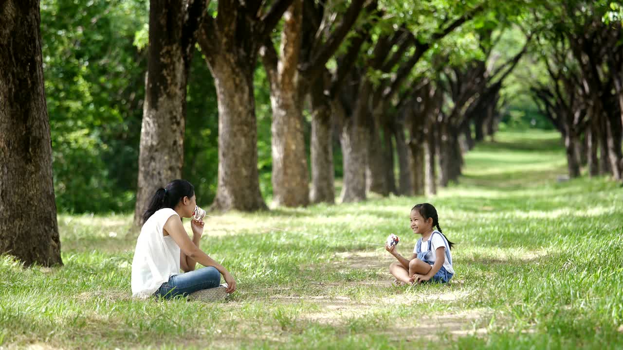 아시아 가족, 어머니와 딸이 공원에서 줄을 는 스트링 폰 놀이 활동을 하고 있습니다.