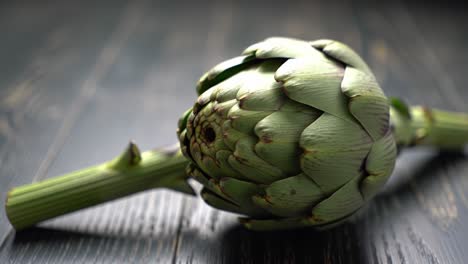 a close-up perspective of a fresh artichoke showcasing its unique structure and vibrant green color against a dark wooden background