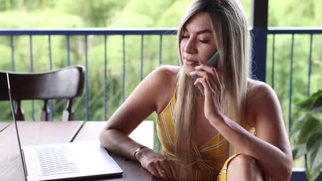 mujer joven trabajando en una computadora portátil en la terraza del restaurante al aire libre