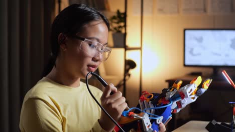 close up of teen asian girl repairing a cyborg hand at home