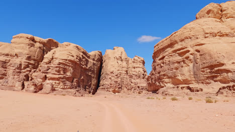 driving on sand towards the rock formations of wadi rum desert