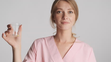 caucasian female doctor holding flask with pills.