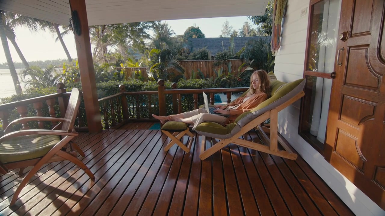 Young Woman Working on Laptop on Tropical Villa Terrace