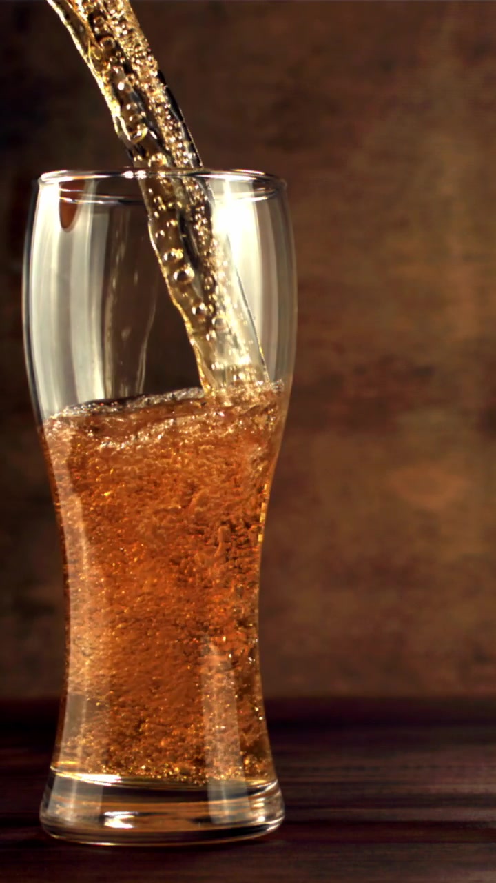 Birra dorata versata in un bicchiere in slow motion