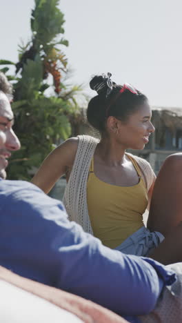 vertical video of happy diverse couple talking on sunny beach, slow motion