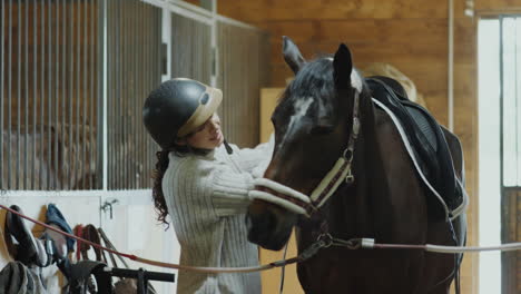 horsewoman brushing horse mane in stable