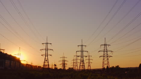 high-voltage electric line at sunset. silhouettes of electric pylons on the setting sun background. electricity distribution station.