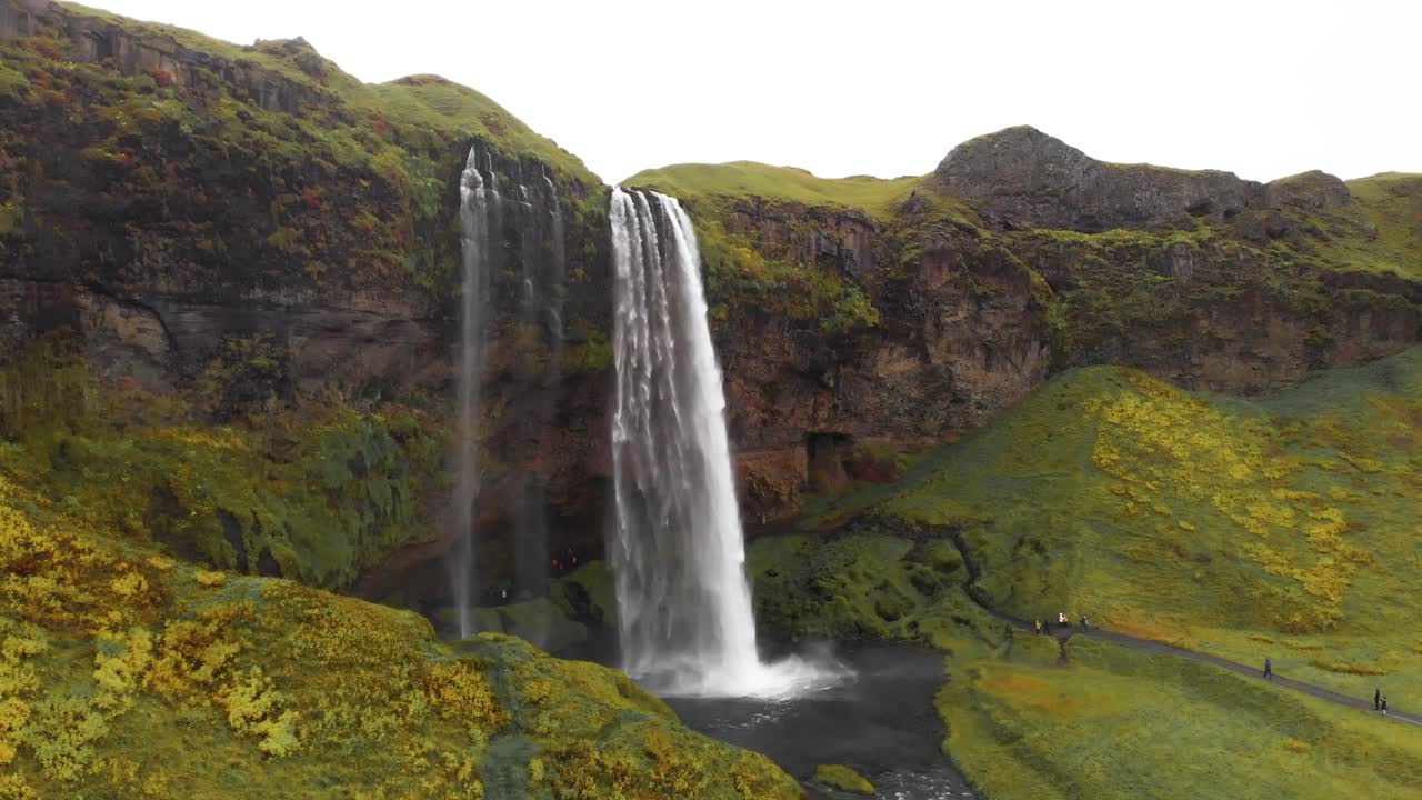 gente caminando por el sendero debajo de la cascada de seljalandsfoss en islandia
