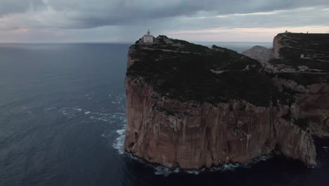 cabo caccia, cerdeña: vista aérea en órbita sobre el faro iluminado durante la puesta de sol y los hermosos colores del cielo