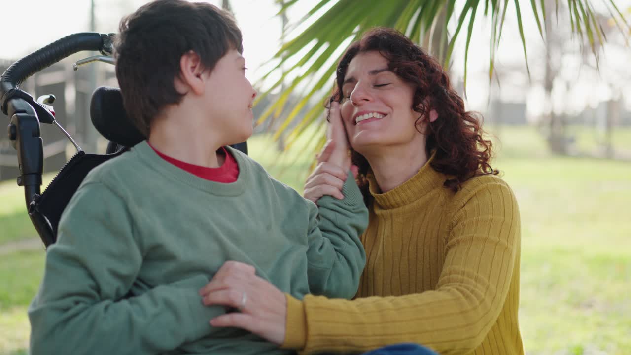 A mother lovingly interacts with her disabled child in a wheelchair