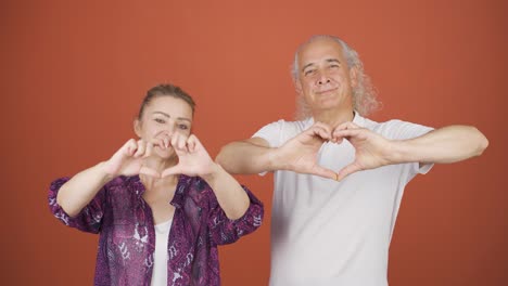 couple making heart sign at camera.