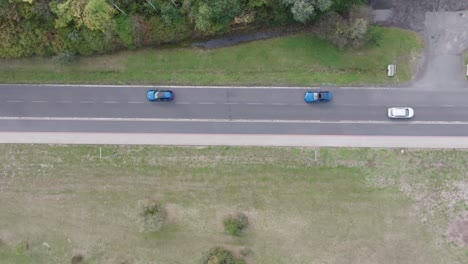 aerial view of blue cars drive on two way road and pass by white car