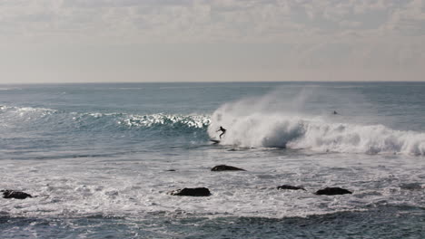 un surfista coge una bonita ola frente a la costa de australia y es tragado por el blanqueo antes de las rocas