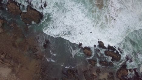 Olas-Rompiendo-En-Las-Rocas-De-La-Costa-Con-Pájaros-Voladores,-Alta-Antena-Vertical