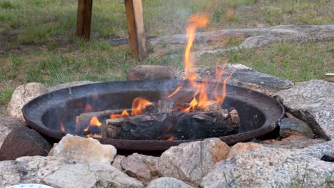 log campfire during day - burning bonfire surrounded by rocks on grass