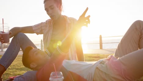 Feliz-Pareja-Gay-Diversa-Haciendo-Picnic-En-El-Paseo-Marítimo,-Cámara-Lenta