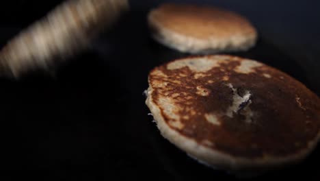 turning half cooked pancakes with a black plastic spatula