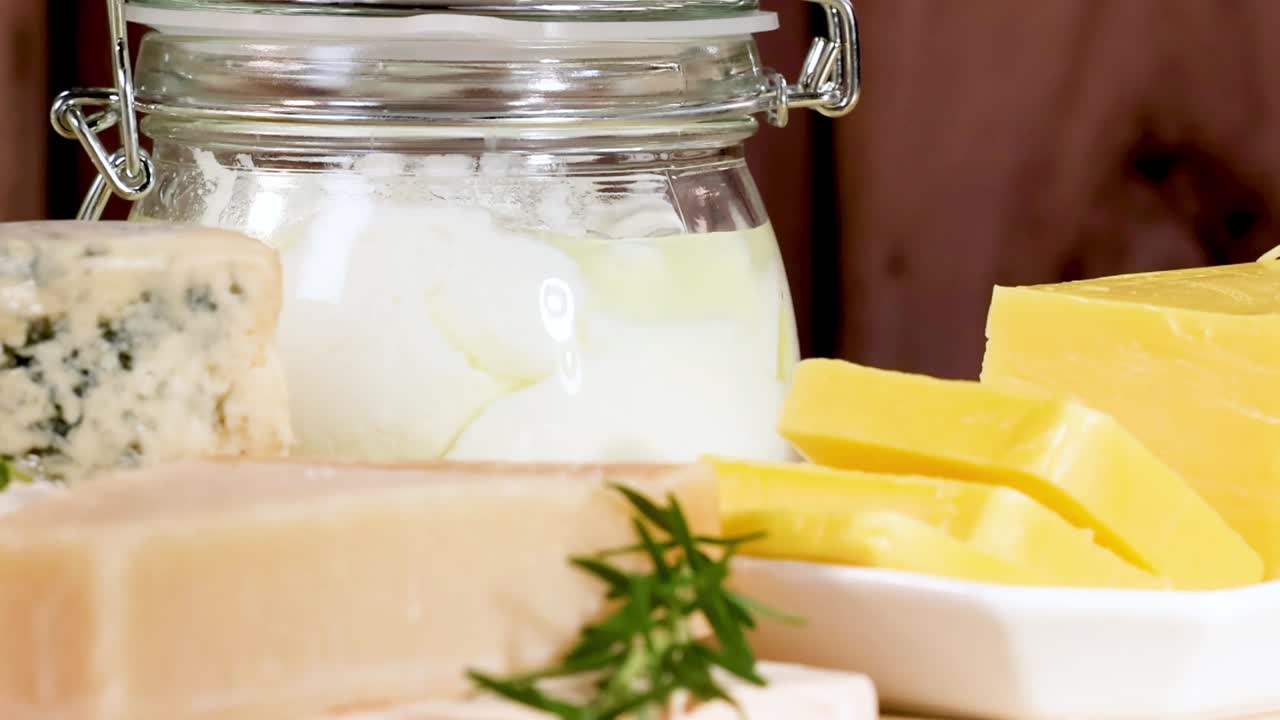 Eine Auswahl an Käsesorten und Milchproduktegläsern, ordentlich auf einem Holztisch arrangiert