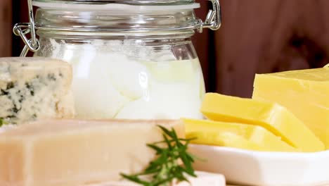 a variety of cheeses and dairy jars arranged neatly on a wooden table.